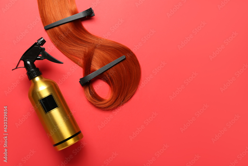 Ginger hair strand with clips and sprayer on red background