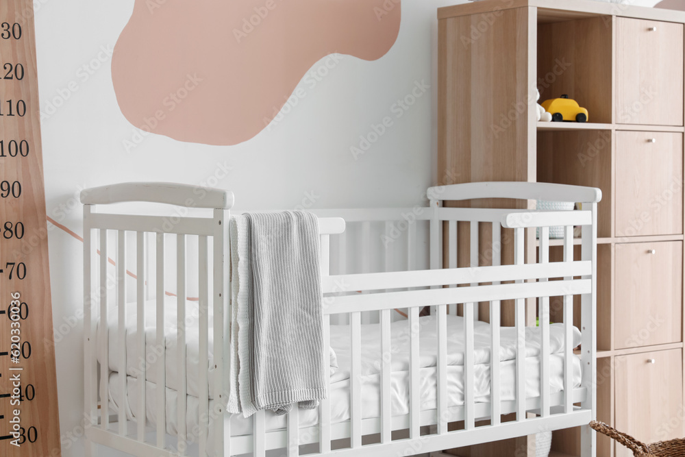 Interior of childrens bedroom with crib, stadiometer and shelving unit