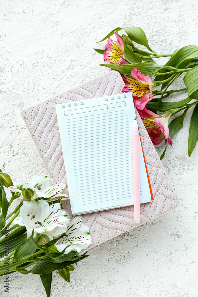 Notebooks, pen and beautiful alstroemeria flowers on light background