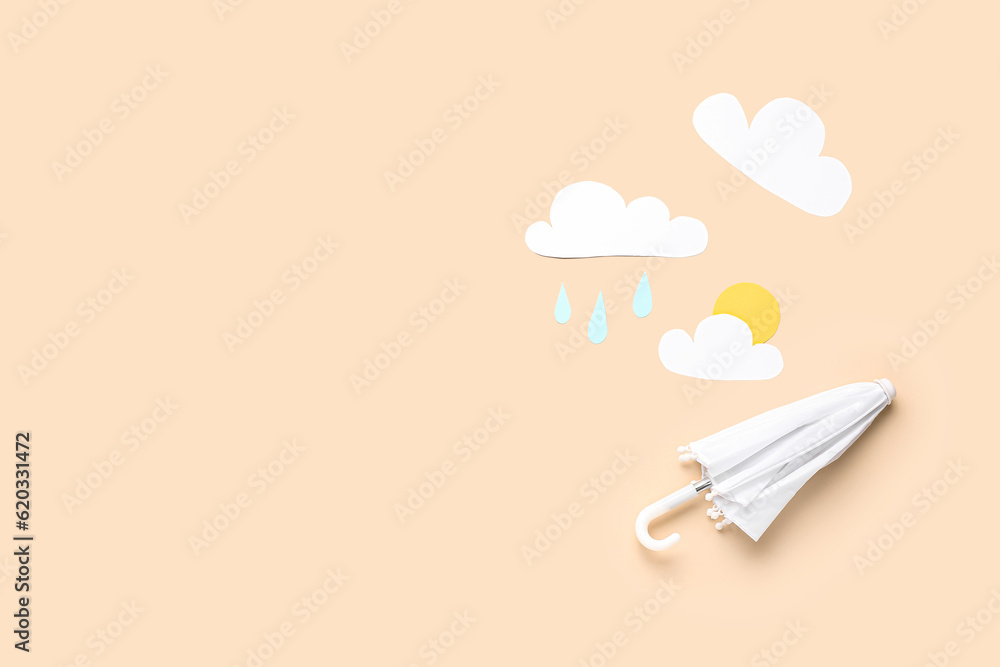 Umbrella with paper clouds, sun and drops on beige background. Weather forecast concept