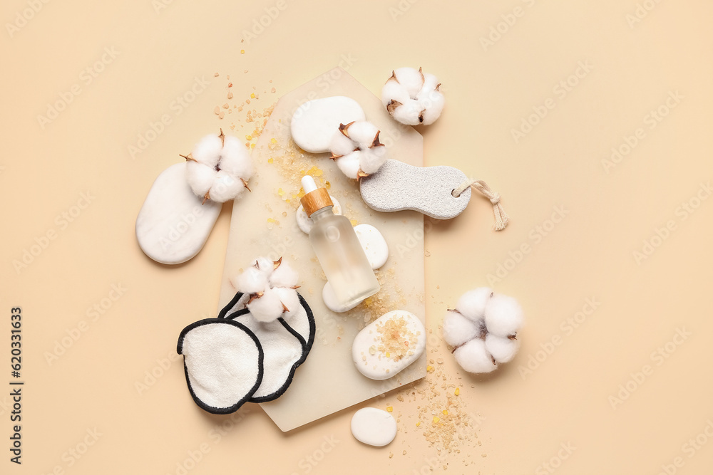 Composition with bottle of essential oil, bath supplies and cotton flowers on color background