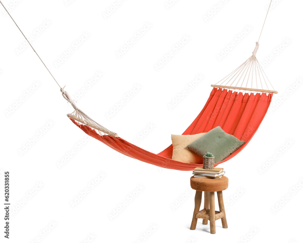 Cozy red hammock with cushions and books with houseplant on soft stool against white background