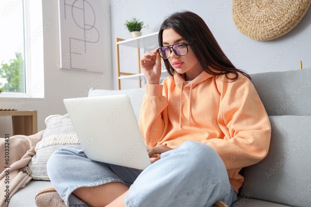 Young woman with laptop wearing glasses at home