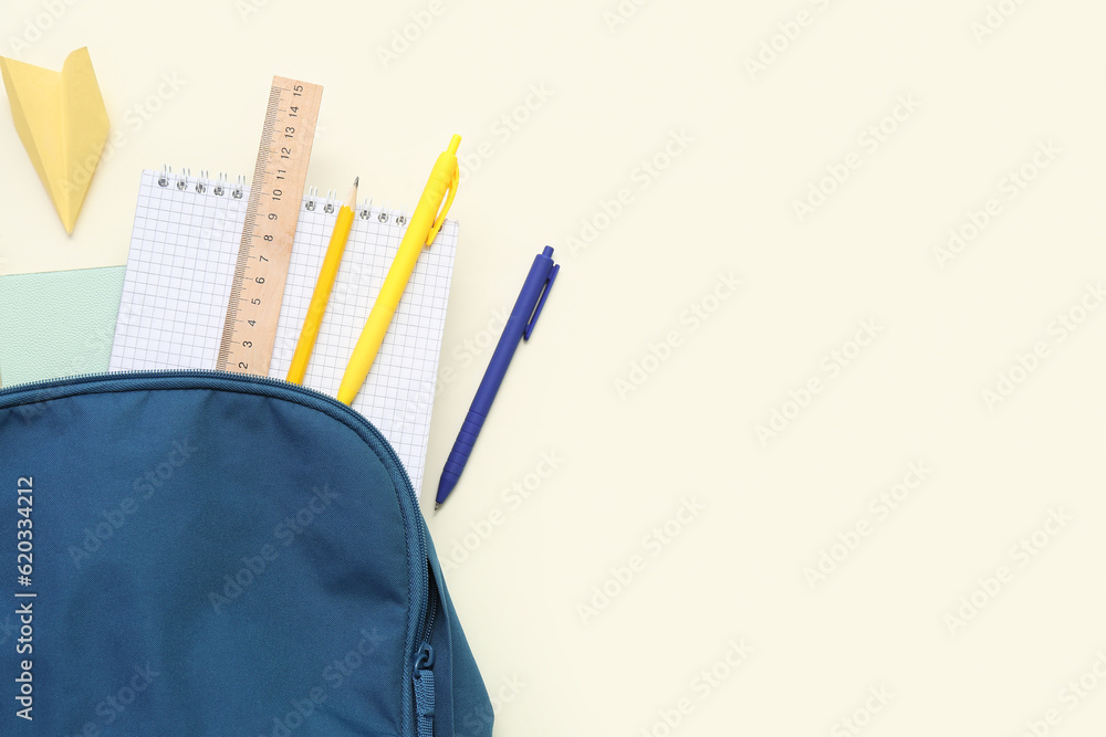 School backpack with paper plane and different stationery on light background