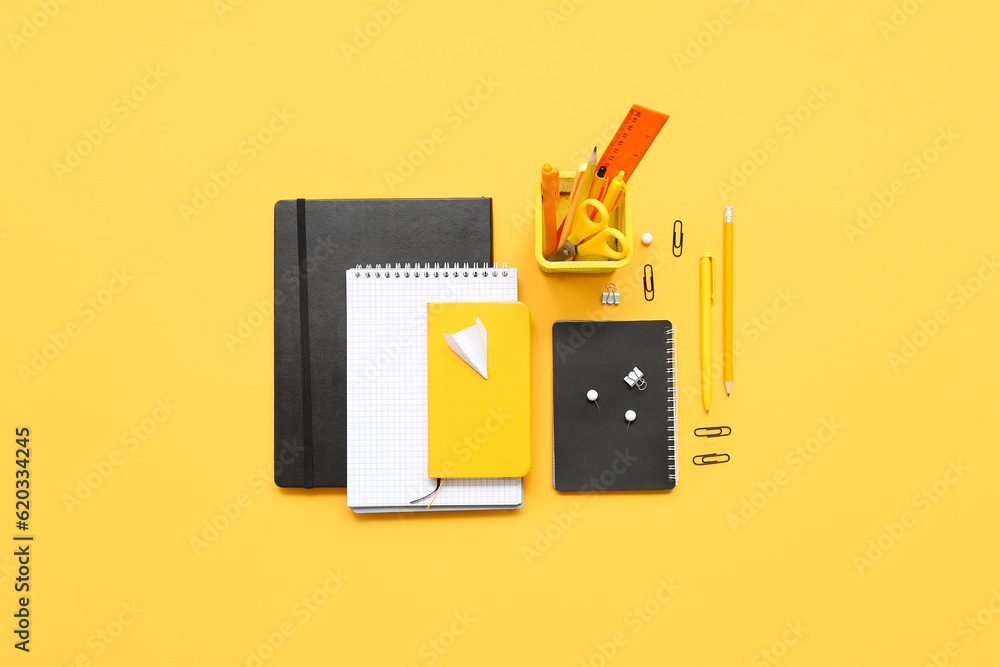 Notebooks, paper plane and different school stationery on orange background