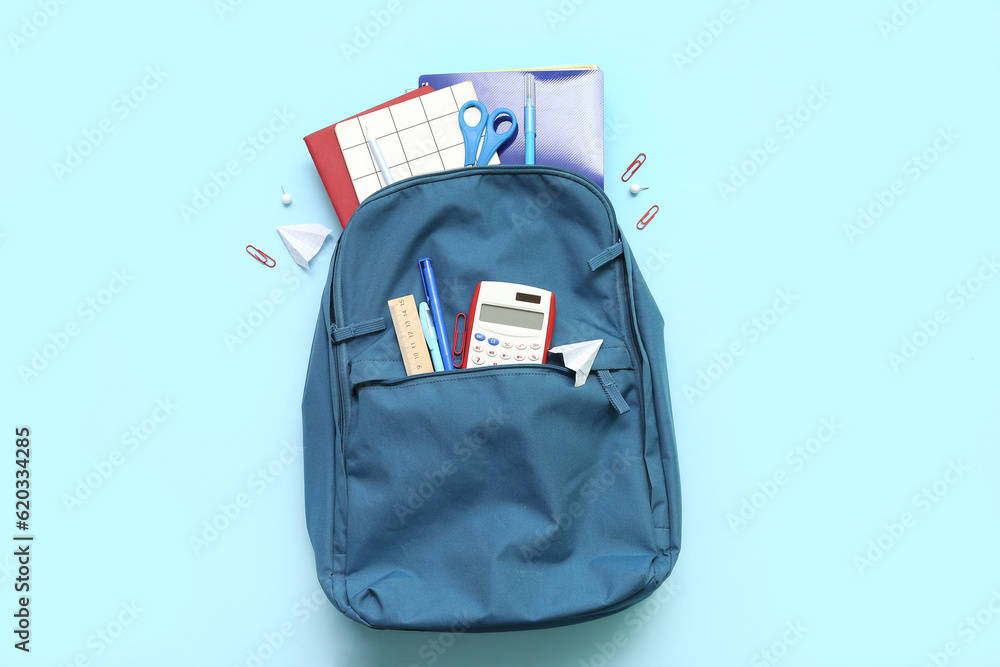 School backpack with different stationery on blue background