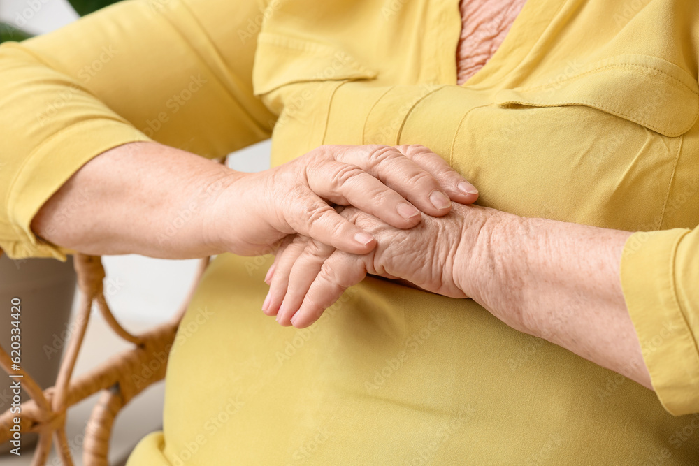 Hands of senior woman resting at home, closeup