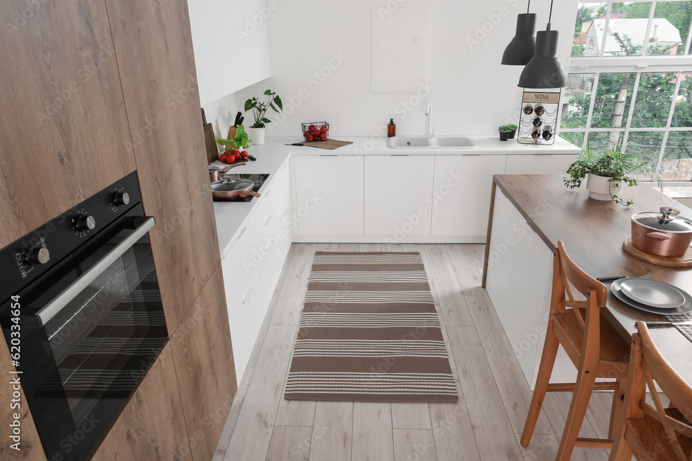 Stylish striped rug in interior of modern kitchen