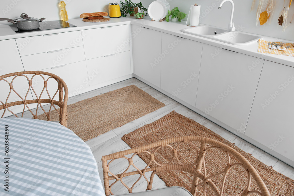 Stylish wicker rugs in interior of modern kitchen