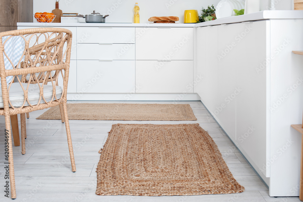 Stylish wicker rugs in interior of modern kitchen