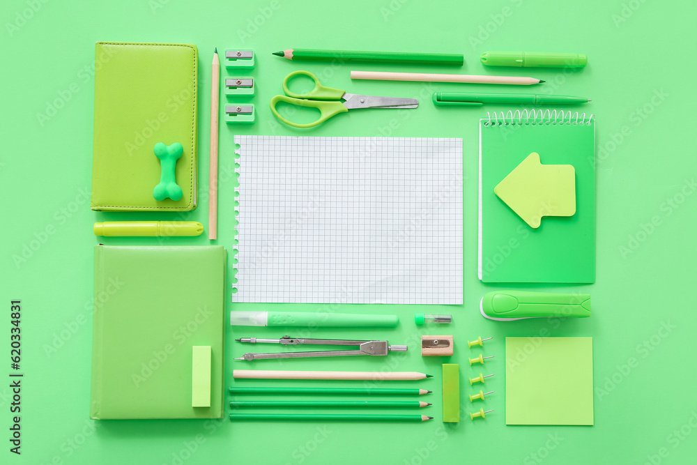 Blank notebook with different stationery on green background