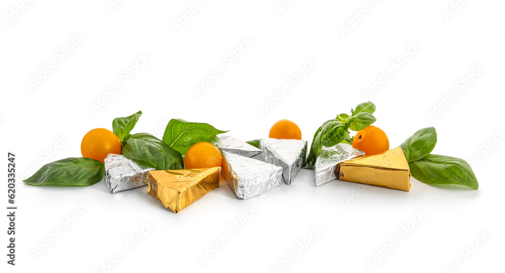 Triangles of tasty processed cheese in foil, cherry tomatoes and basil leaves on white background