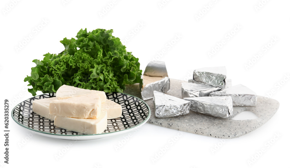 Plate with triangles of tasty processed cheese and lettuce on white background