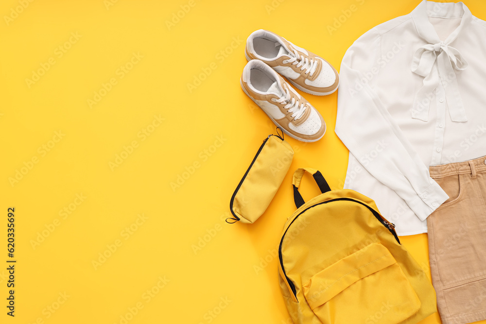 Composition with stylish school uniform, backpack, sneakers and pencil case on orange background