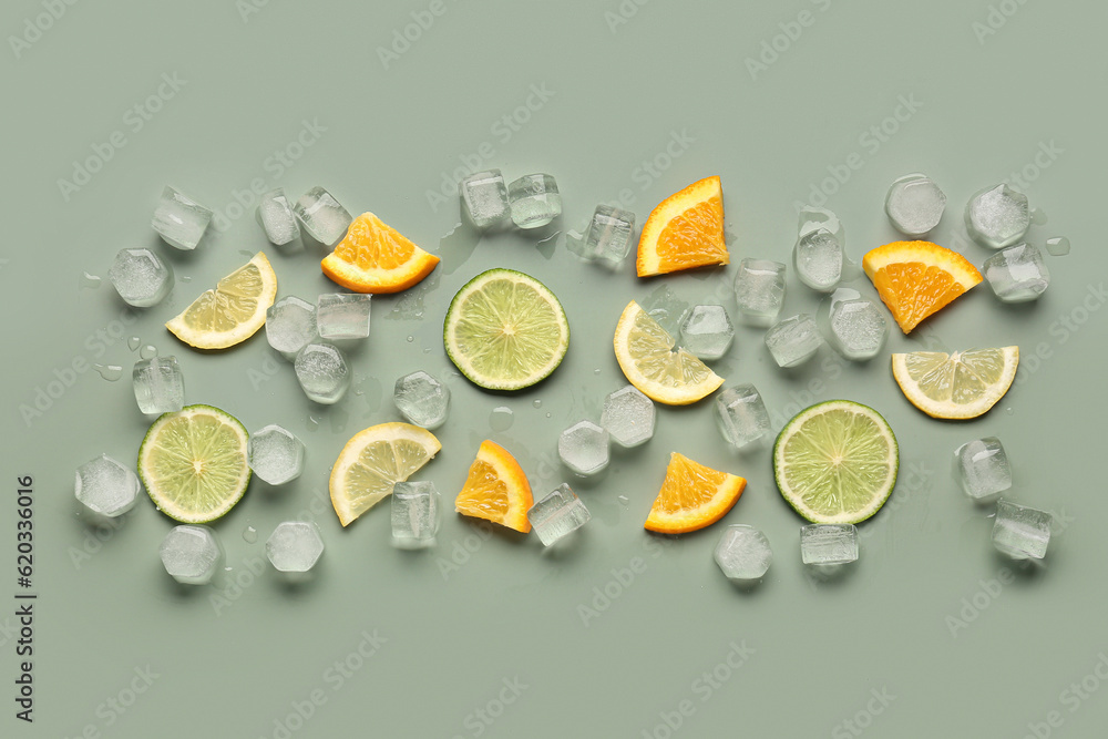 Citrus slices with ice cubes on green background