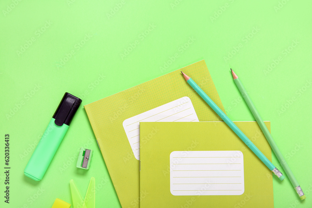 Notebooks with different stationery on green background