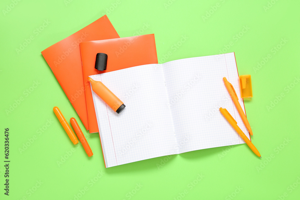 Orange notebooks with markers on green background