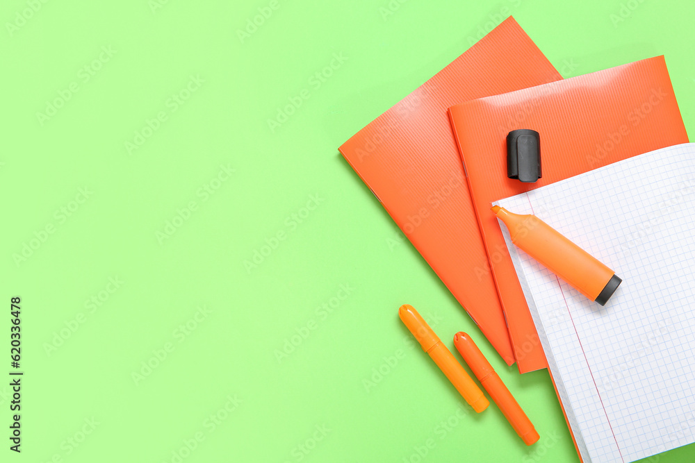 Orange notebooks with markers on green background