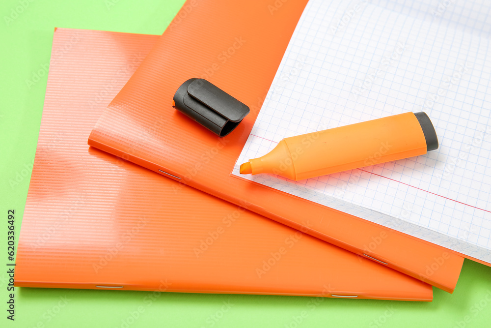 Orange notebooks with markers on green background