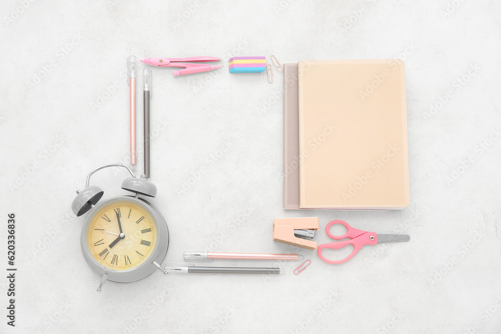 Alarm clock with different stationery on beige background