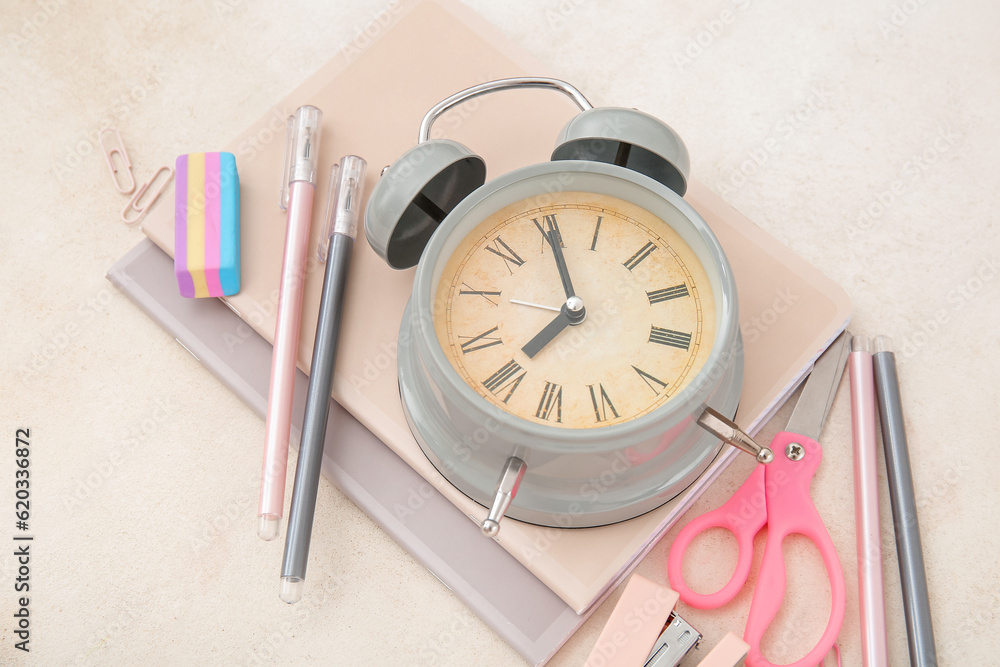 Alarm clock with different stationery on beige background