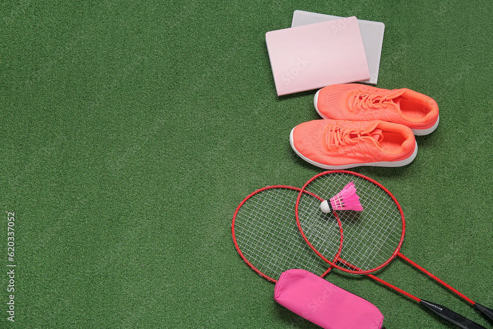 Sneakers with rackets, badminton shuttlecock and stationery on color background