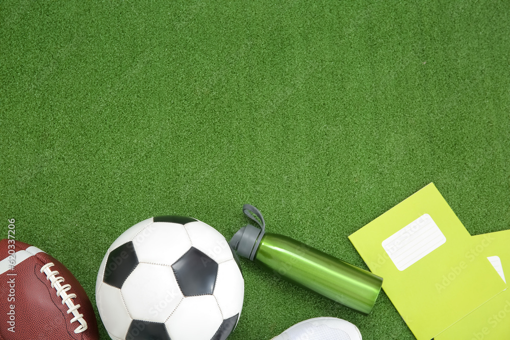 Sneakers with sport balls, bottle of water and notebooks on color background