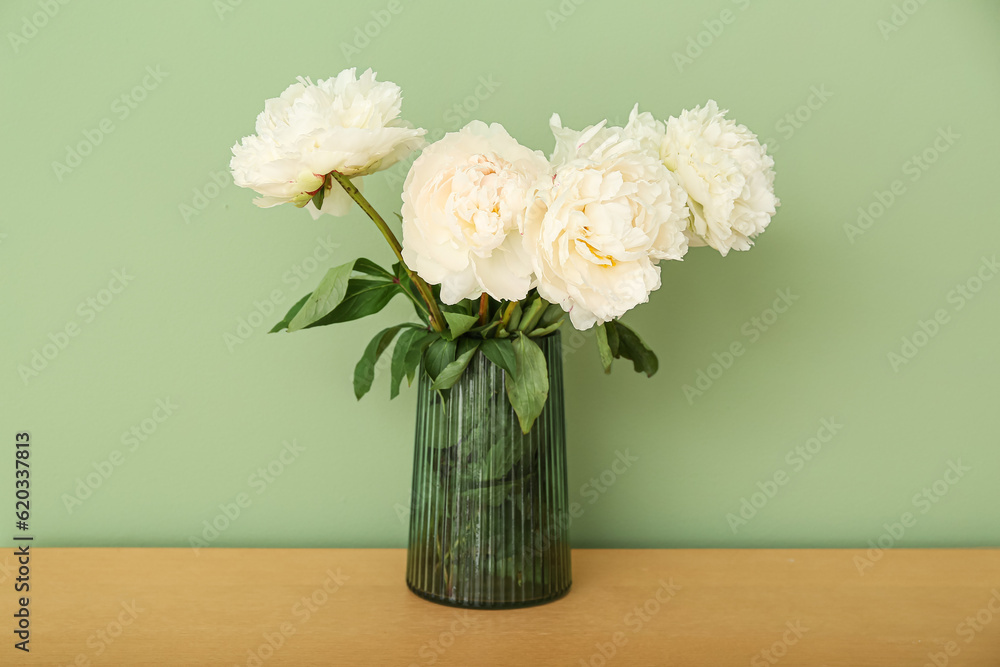 Vase of white peonies on dresser near green wall