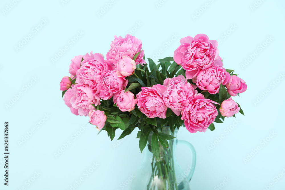 Vase of pink peonies on blue background