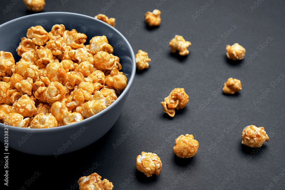 Bowl with tasty popcorn on black background