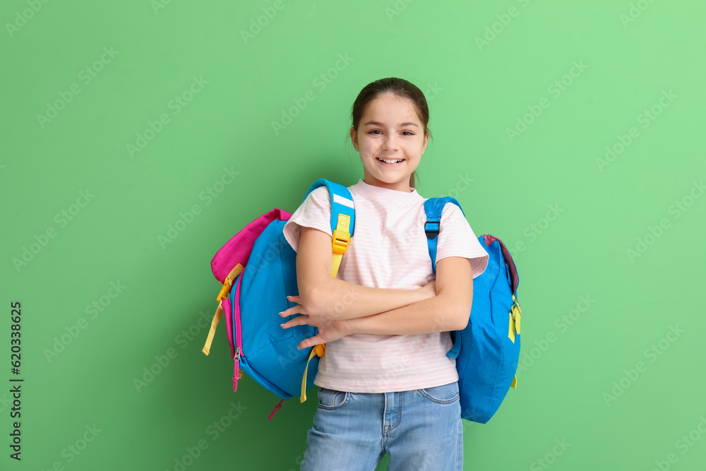 Little girl with backpacks on green background