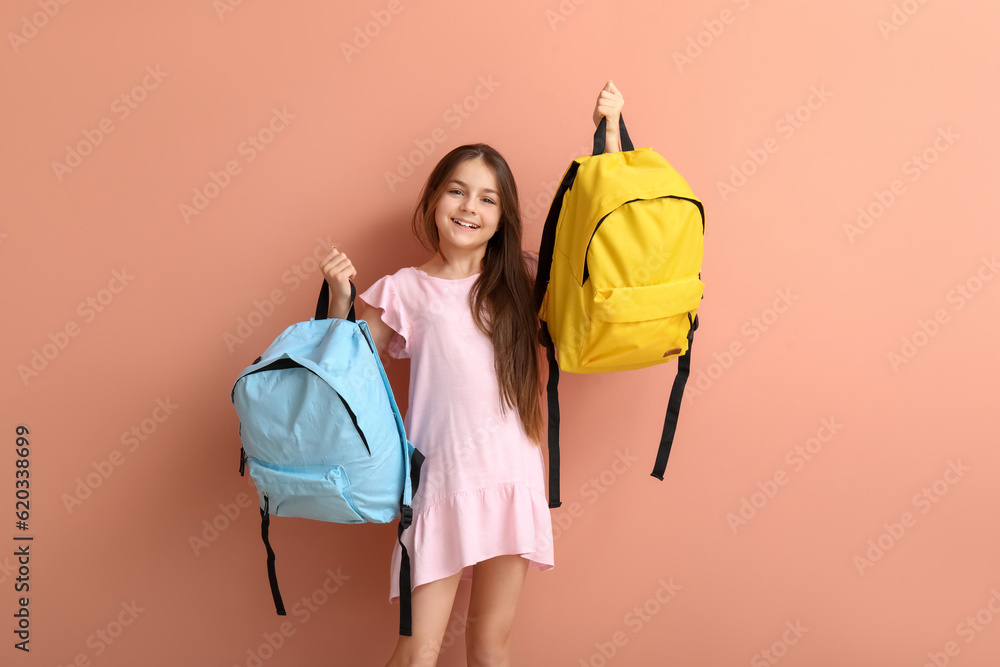 Little girl with backpacks on pink background