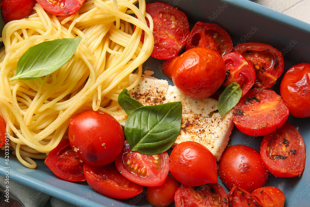 Baking dish of tasty pasta with tomatoes and feta cheese on table