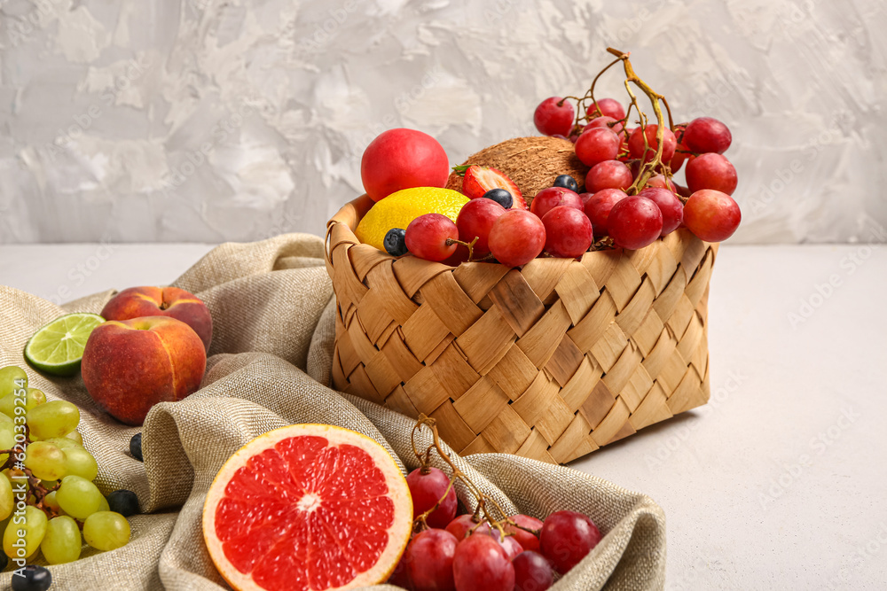 Wicker basket with different fresh fruits on white background