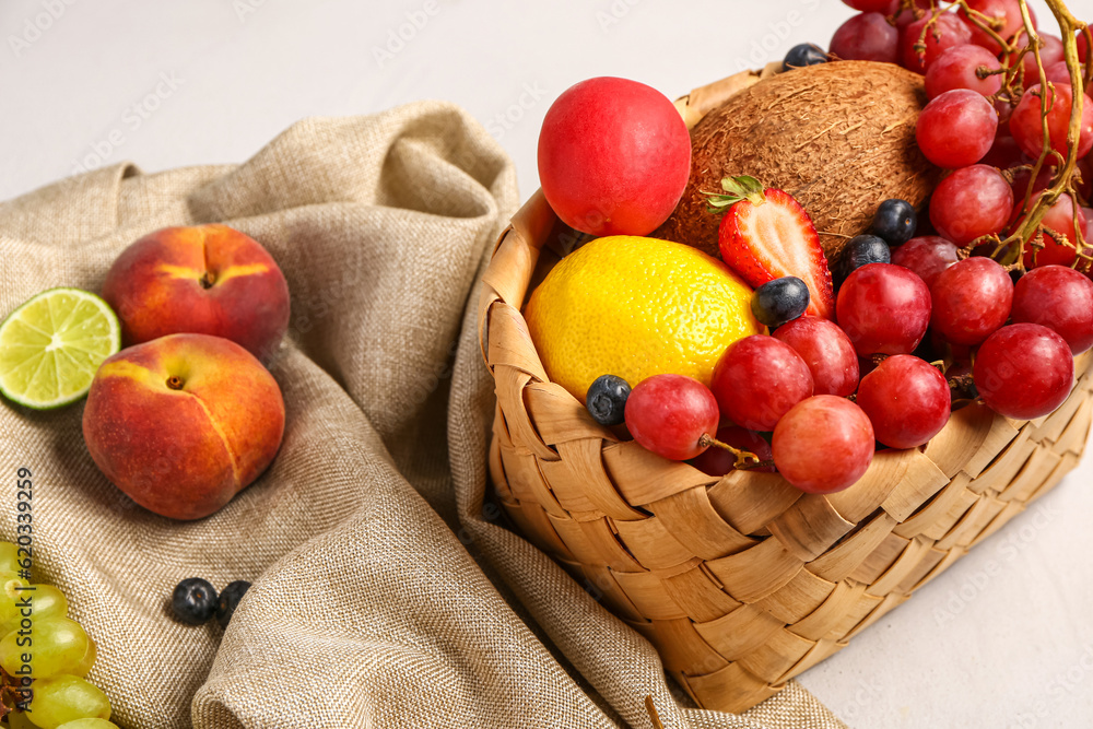 Wicker basket with different fresh fruits on white background