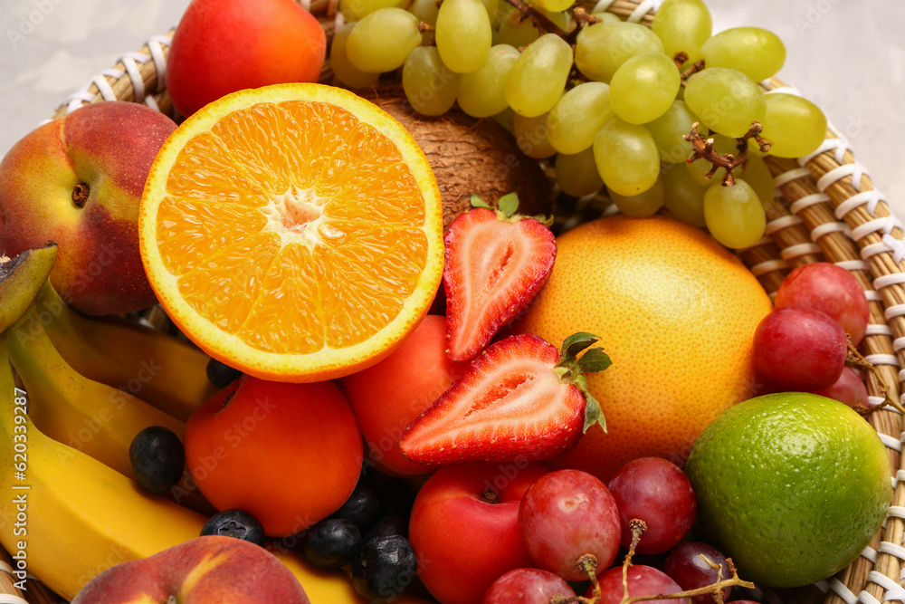 Wicker bowl with different fresh fruits, closeup