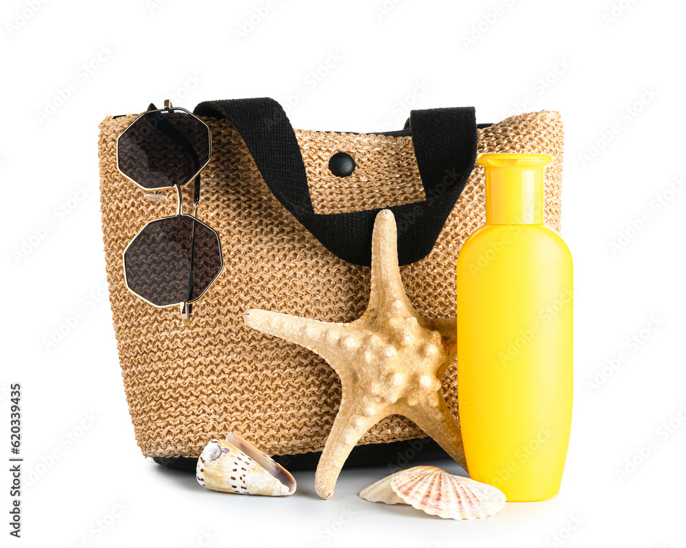 Wicker bag with sunglasses, starfish and bottle of sunscreen cream isolated on white background