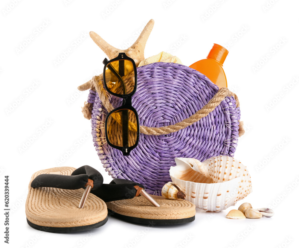 Wicker bag with flip flops, sunglasses and bottle of sunscreen cream isolated on white background