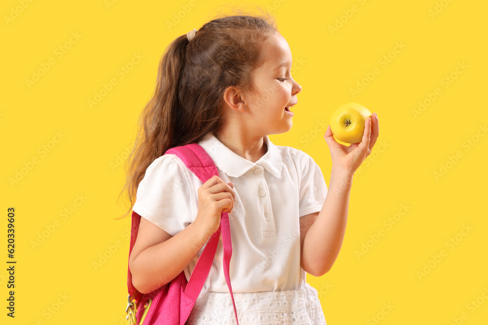 Little schoolgirl with apple on  yellow background