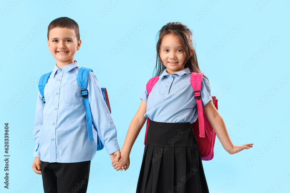 Little schoolchildren holding hands on light blue background