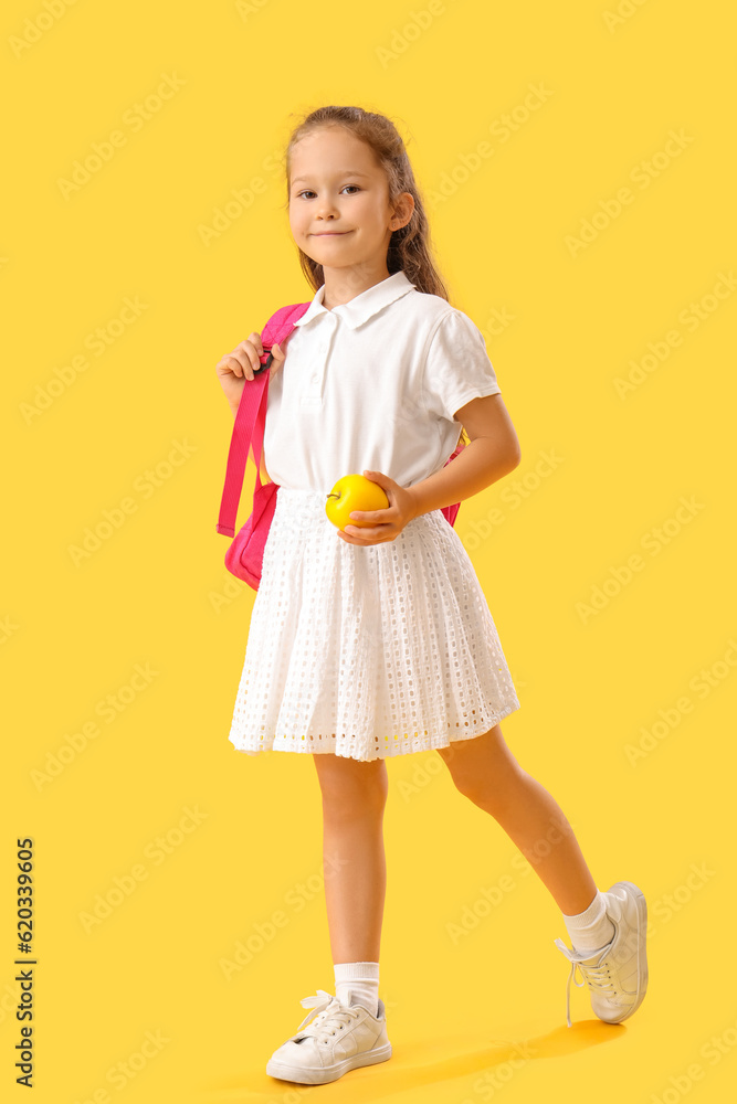 Little schoolgirl with apple on  yellow background