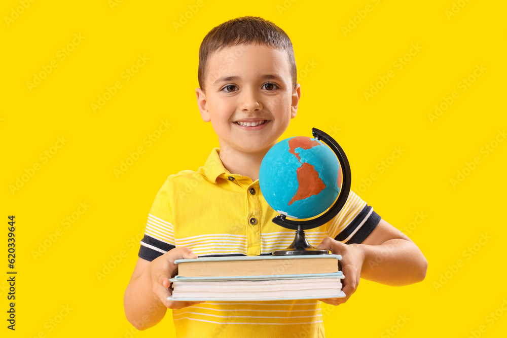 Little schoolboy with books and globe on yellow background