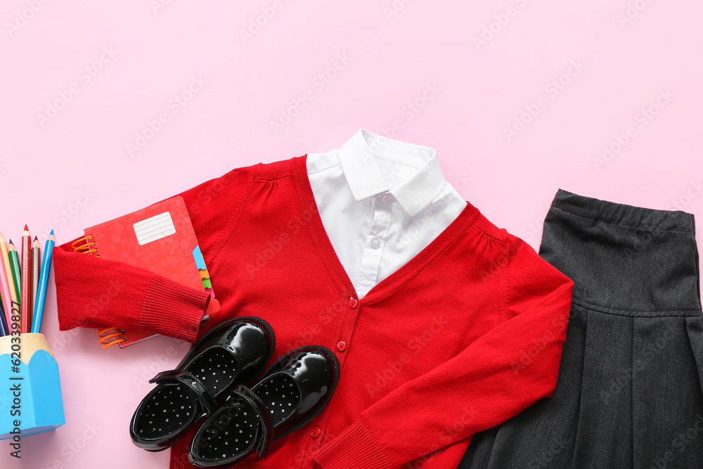 Stylish school uniform with stationery on pink background