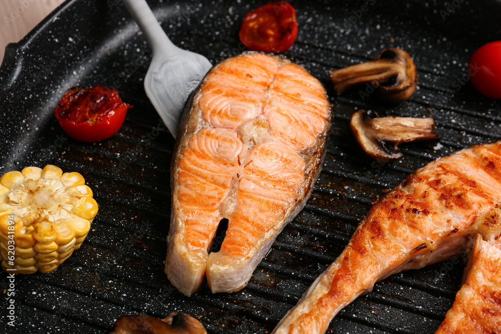 Tasty grilled salmon steaks in frying pan, closeup