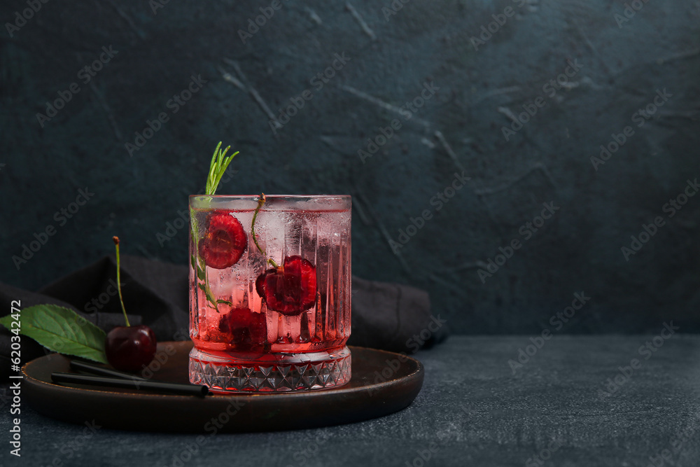 Glass of tasty cherry lemonade with rosemary on dark background