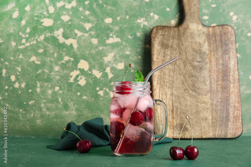 Mason jar of tasty cherry lemonade and mint on green table