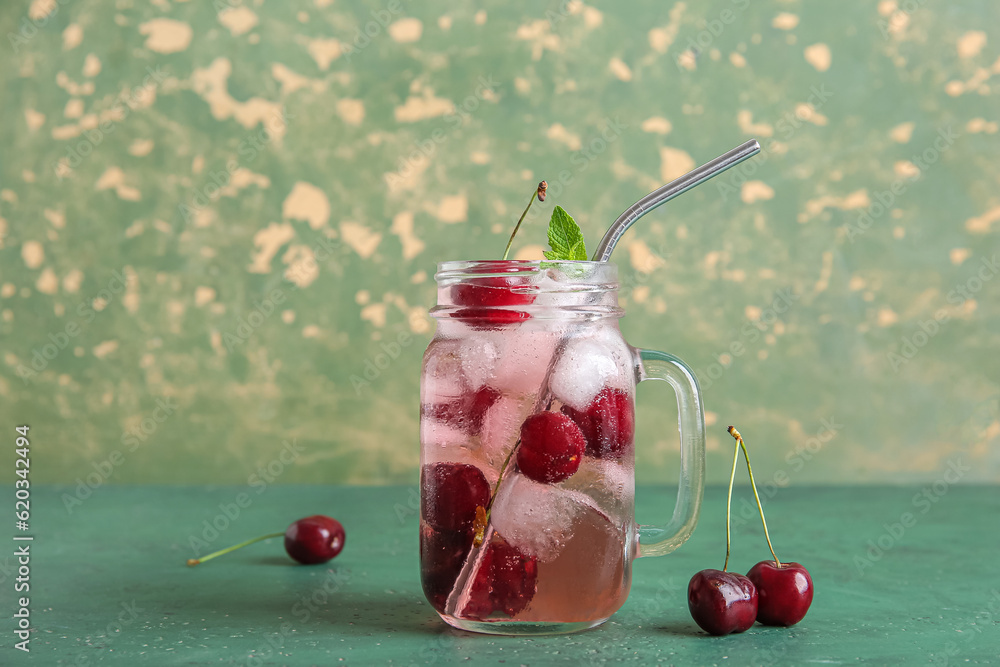 Mason jar of tasty cherry lemonade and mint on green table