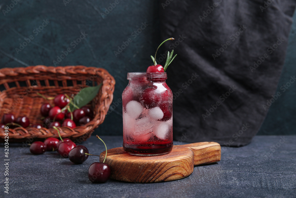 Wooden board with jar of tasty cherry lemonade and rosemary on dark background