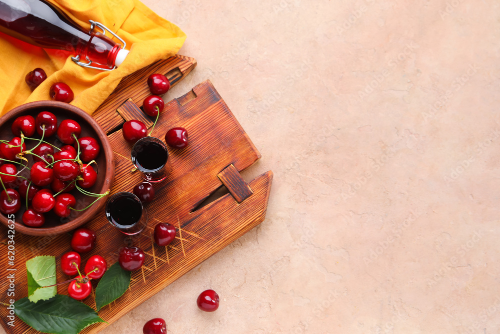 Wooden board with shots and bottle of sweet cherry liqueur on pink background