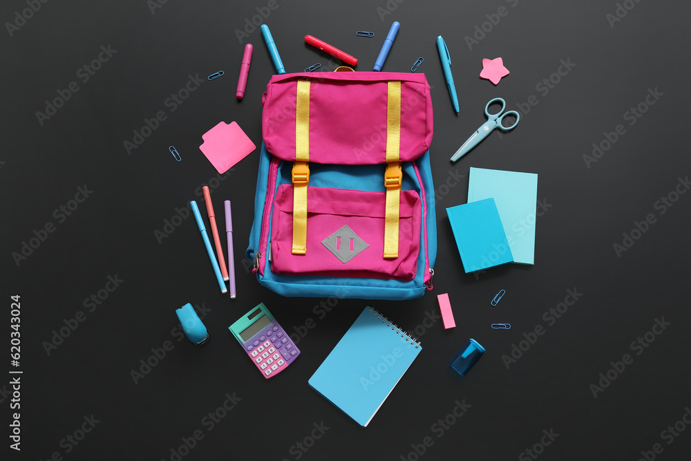 Colorful school backpack with different stationery on black background